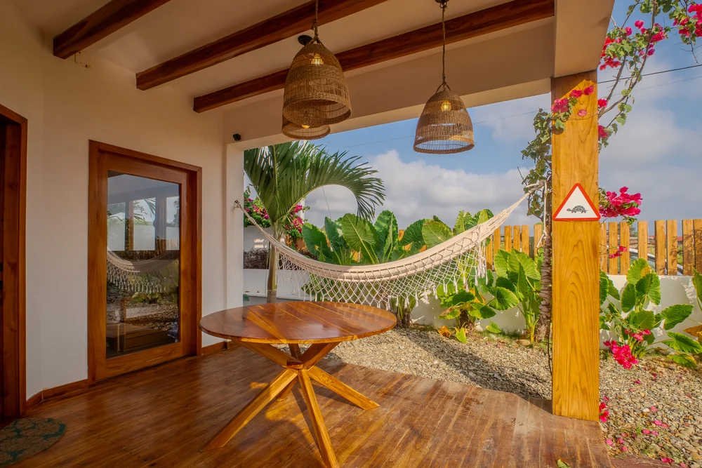 Terraza con mesa de madera, hamaca y jardín tropical