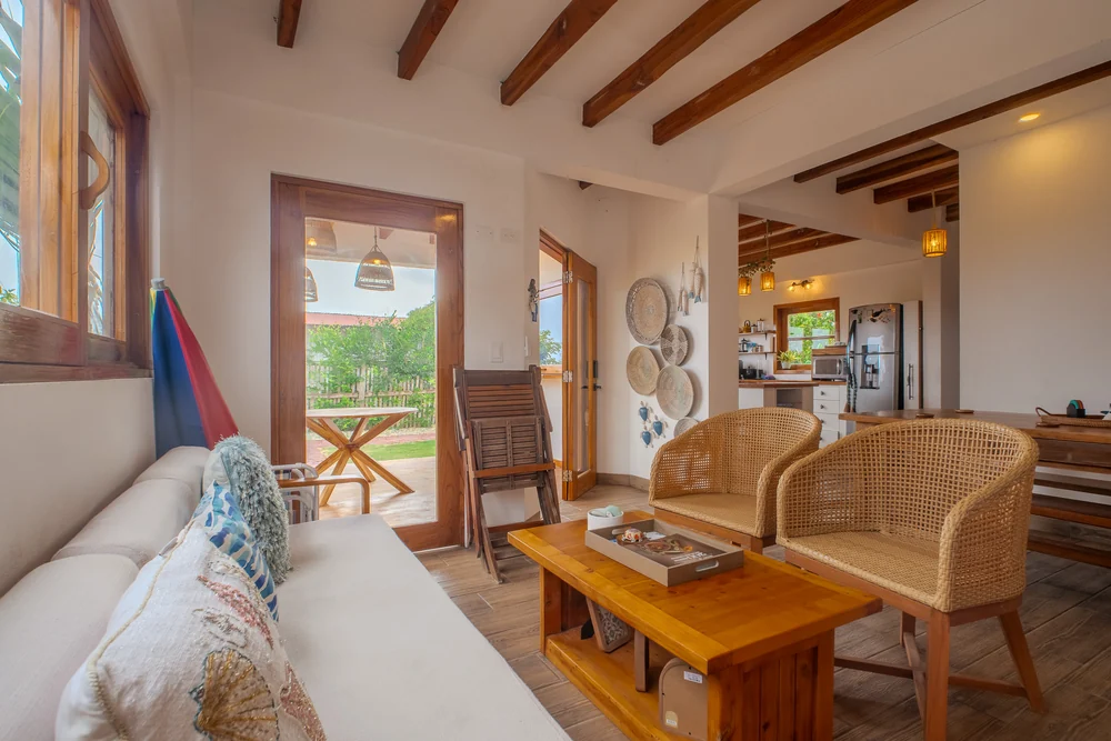 Salón con sofá, sillones de mimbre y puertas abiertas al exterior