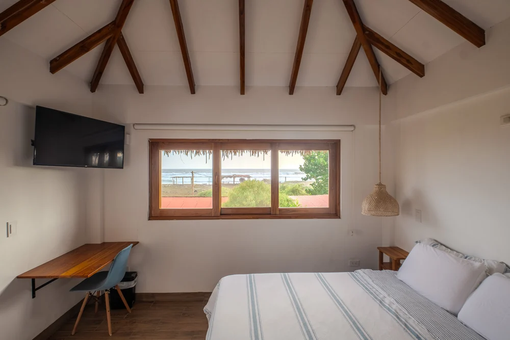 Habitación luminosa con cama queen y ventana hacia el mar